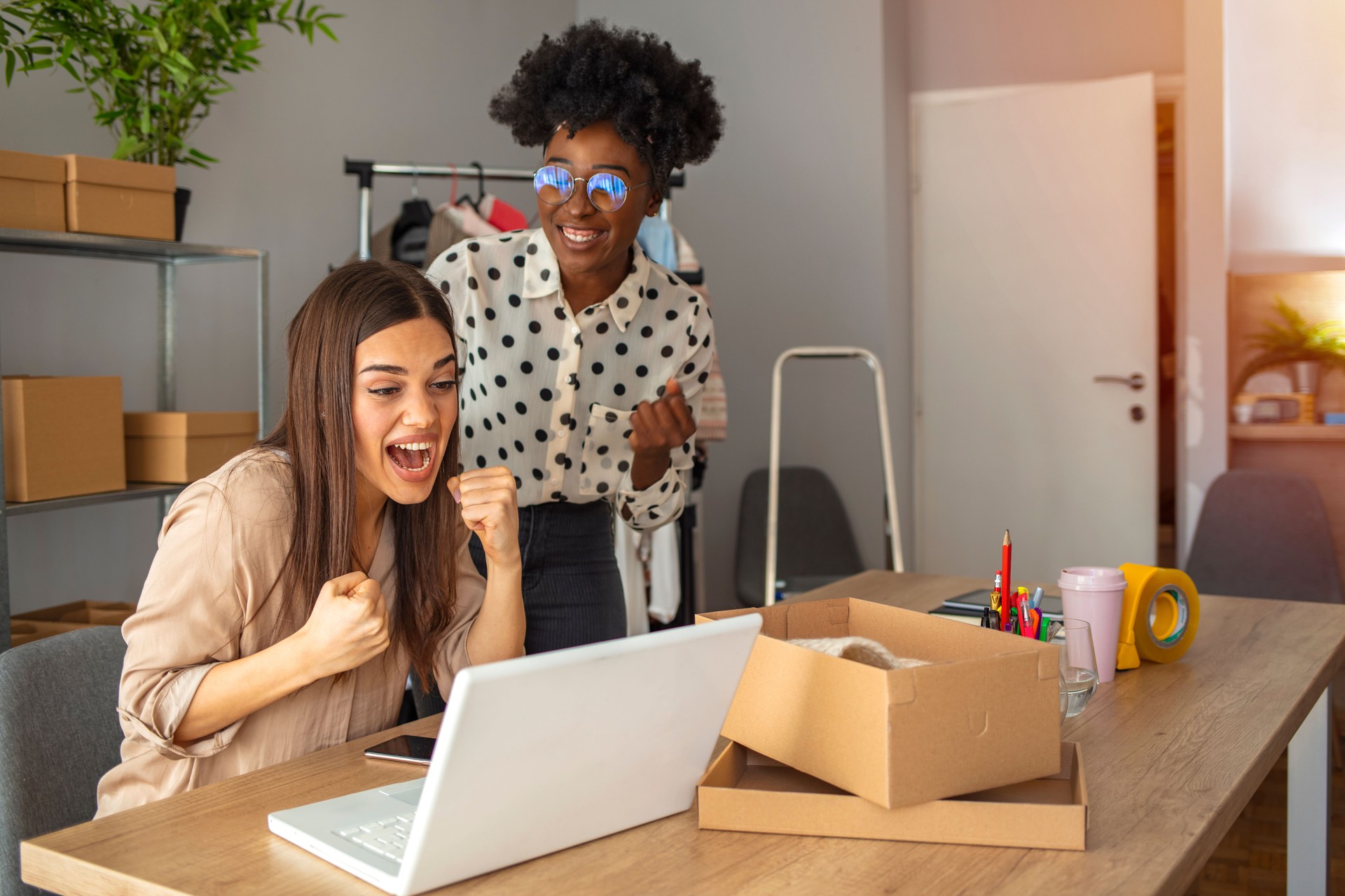 Two cheerful young people using computer and celebrating their success